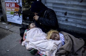 A Syrian refugee woman begs with her children on the street  in the Beyoglu district of Istanbul on April 17, 2015. AFP PHOTO / BULENT KILIC