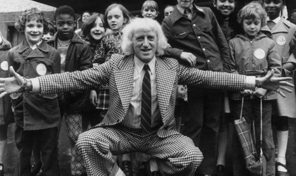 Predator Savile poses with children taking part in his Jim ll Fix It show in 1974