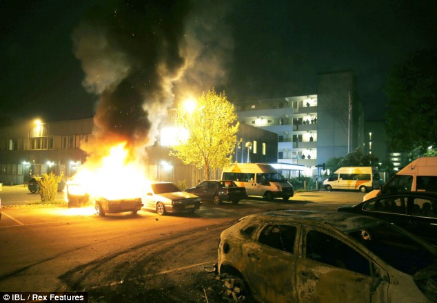 Stockholm burning: A car is set ablaze in a suburb north of the Swedish capital last night