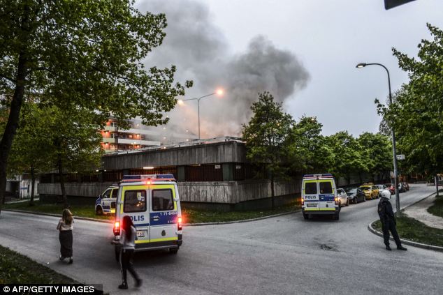 Policemen secure an apartment building after youths rioted in Husby, northern Stockholm