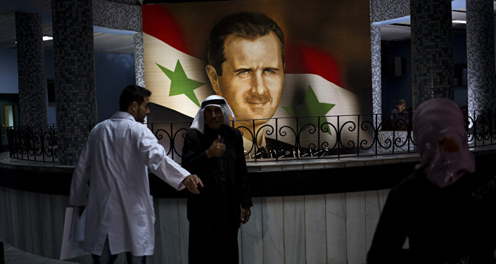 People walk through the Damascus General Hospital past a portrait of the President Bashar Assad in Damascus, Syria, Sunday, May 4, 2014