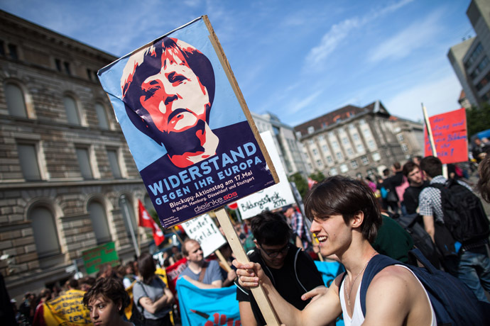 A protester holds a banner featuring German chancellor Angela Merkel reading 'resistance against her Europe' during a Blockupy movement protest on May 17, 2014 in Berlin. The demonstration is directed against the government's refugee policy. AFP PHOTO / DPA/ MAJA HITIJ /GERMANY OUT