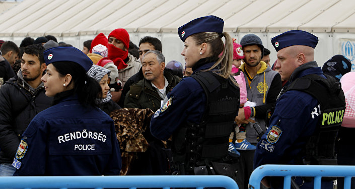 Hungarian police officers keep order as migrants wait to board a train towards Serbia.