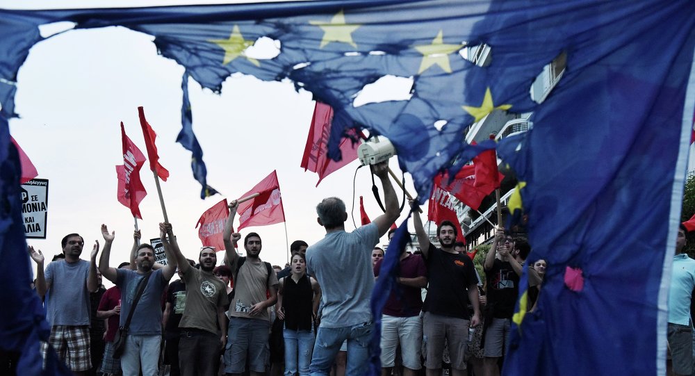Members of left wing parties shout slogans behind a burning European Union flag during an anti-EU protest in the northern Greek port city of Thessaloniki, Sunday, June 28, 2015