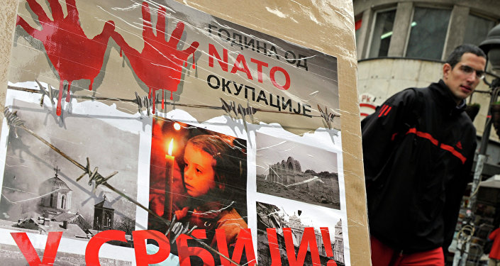 A man walks past a poster with the reading “Ten years of NATO occupation of Serbia”, and displaying images from 1999 NATO air campaign against Serbia and Montenegro, in Belgrade on March 23, 2009.