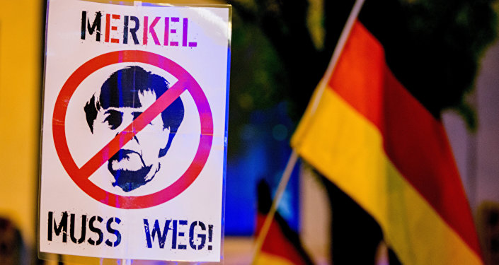 A participant of a rally of the Pegida movement (Patriotische Europaeer gegen die Islamisierung des Abendlandes, which translates to Patriotic Europeans Against the Islamisation of the Occident) holds a sign depicting German chancellor Angela Merkel and reading Merkel must go (Merkel muss weg) in Munich, southern Germany, on November 9, 2015