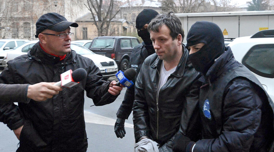 Marcel Lazar Lehel, aka Guccifer, is escorted by masked policemen in Bucharest after his arrest in 2014. © Silviu Matei