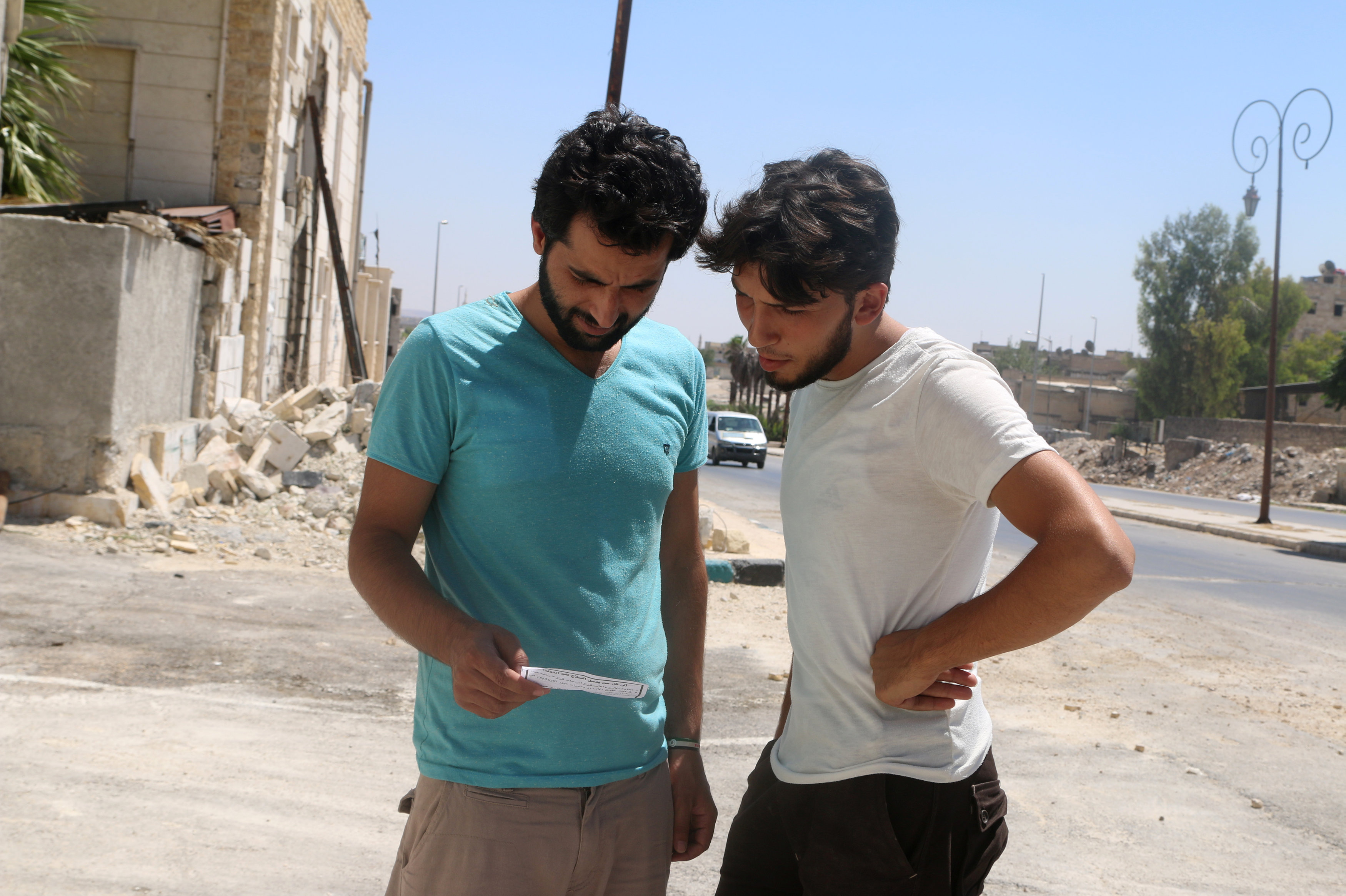 Men read one of the leaflets dropped by the Syrian army over opposition-held Aleppo districts asking residents to cooperate with the military and calling on fighters to surrender, Syria July 28, 2016