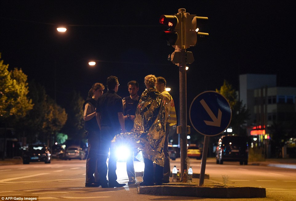 Police officers speak with people at a closed street near the shopping mall Olympia Einkaufzentrum OEZ in Munich following the attack