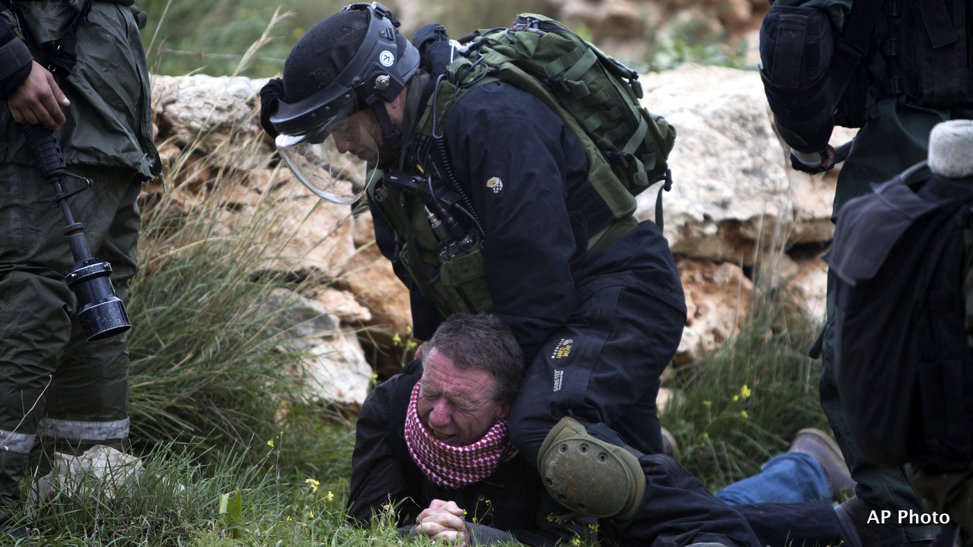 An Israeli border policeman detains a Palestinian protester during a weekly demonstration against Israel's separation barrier in the West Bank village of Bilin near Ramallah, Friday, Feb. 13, 2015. 