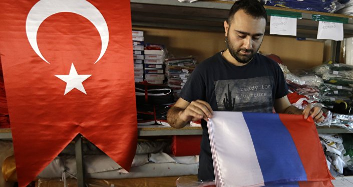 An employee of a flag-making factory folds a Russian flag as a Turkish flag adorns the display at left, in Istanbul, Tuesday, Aug. 9, 2016