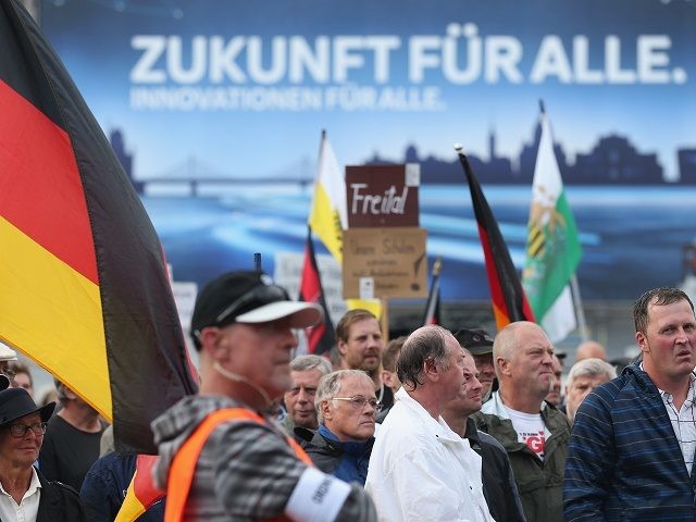 DRESDEN, GERMANY - JULY 27:  An advertising billboard reads: "Future for all" behind supporters of the Pegida movement listening to speakers during their weekly gathering on July 27, 2015 in Dresden, Germany. A Pegida leader spoke out against any form of violence against refugees yet called for a radical change to Europe's liberal policy of accepting so many refugees and migrants. Pegida is also critical of Islam and many of its supporters see Muslim immigration as a threat to Germany. Meanwhile the German Red Cross recently opened a tent camp to house 800 mostly Syrian refugees that quickly resulted in violent protests by neo-Nazi supporters who scuffled with both refugee-supporters and police. Germany is currently struggling to accomodate and process a record-number of asylum seekers from the Middle East, Africa and the Balkans.  (Photo by Sean Gallup/Getty Images)