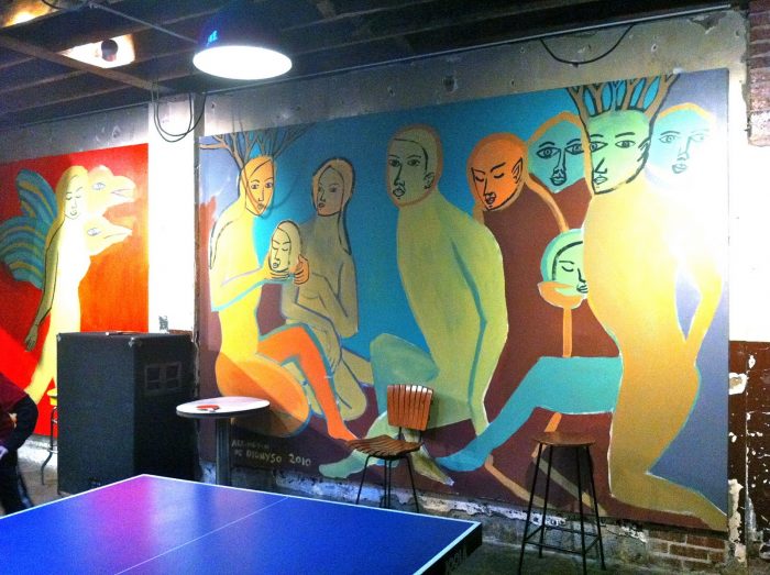 This is the mural prominently on display at Comet Ping Pong. It depicts strange people holding the heads of smaller people.