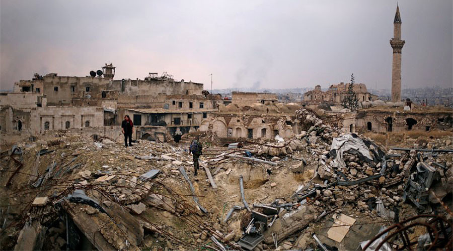 A member of forces loyal to Syria's President Bashar al-Assad stands with a civilian on the rubble of the Carlton Hotel, in the government controlled area of Aleppo, Syria December 17, 2016. © Omar Sanadiki