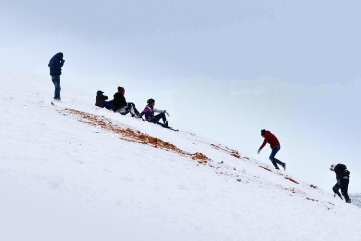 Children sledge down snow covered dunes in the Algerian town Aïn Séfra. Click to enlarge