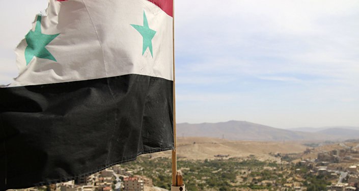 In this photo taken on Sunday, Oct. 18, 2015, a Syrian flag flies above the village of Maaloula, north of Damascus, Syria
