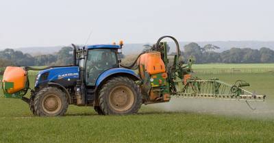 Tractor on an agricultural farm field spraying pesticides
