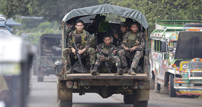In this June 9, 2017, photo, soldiers ride a military vehicle on the outskirts of Marawi city, southern Philippines. The Philippine military says 13 marines have been killed in fierce fighting with Muslim militants who have laid siege to southern Marawi city.
