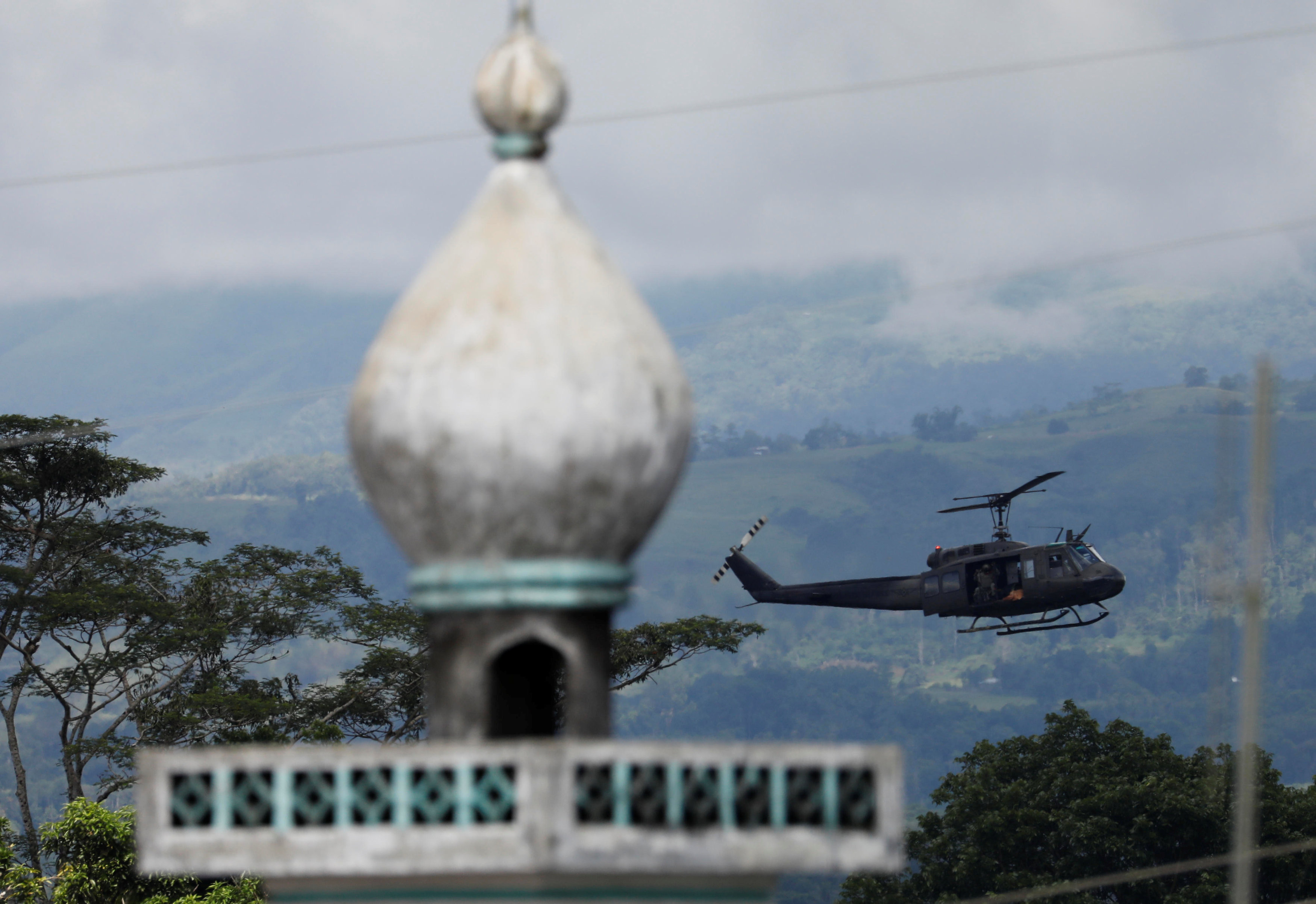 A military helicopter flies past a mosque in Marawi. Photo: Reuters