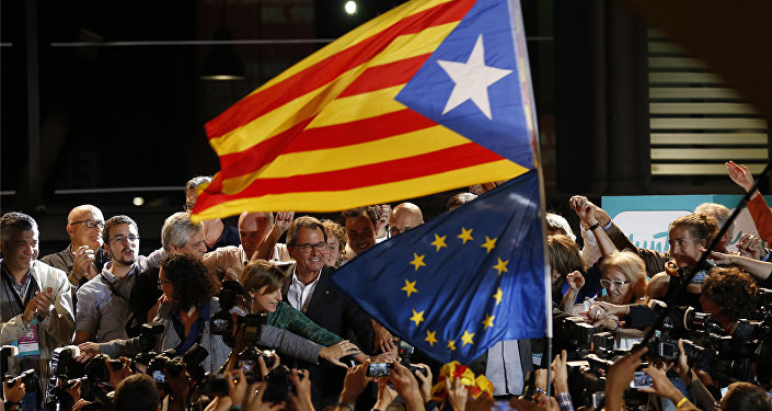 A estelada or pro independence flag and a European Union flag are waved in front of the President of Democratic Convergence of Catalonia Artur Mas, center in front of supporters in Barcelona, Spain, Sunday Sept. 27, 2015