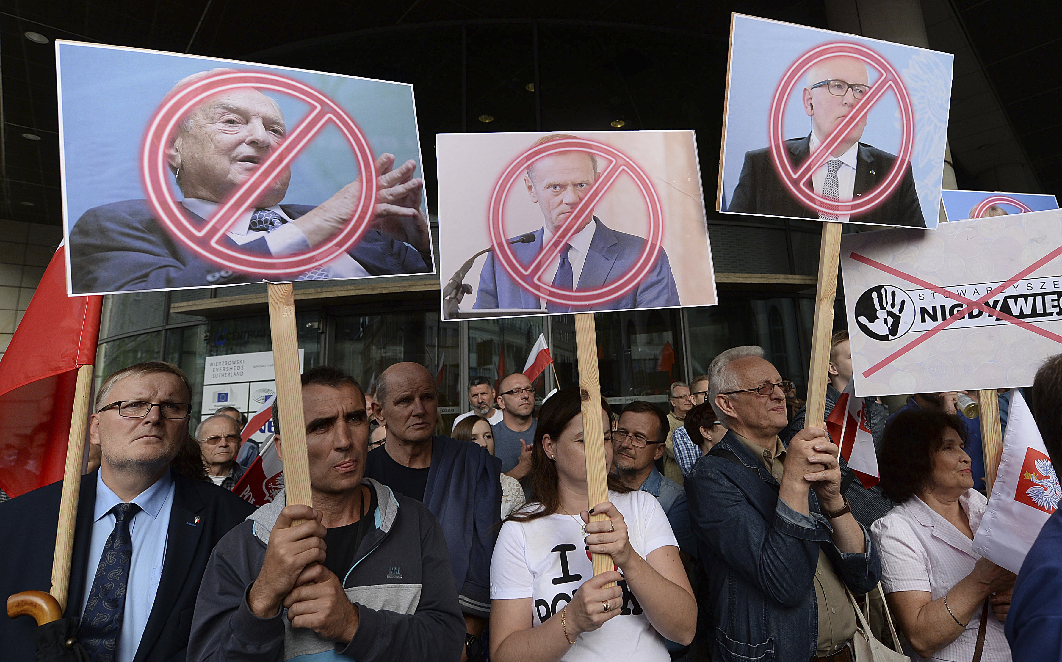   People demonstrate, outside the office of the ruling party leader Jaroslaw Kaczynski, holding banners with the images of from left, financier George Soros ,President of the European Council Donald Tusk and First Vice-President of the European Commission Frans Timmermans, during a protest, in Warsaw, Poland, Wednesday, July 26, 2017