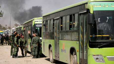 Syrian troops stand next to buses carrying militants and their families before they are evacuated, at Harasta highway outside Jobar, in Damascus, Syria March 25, 2018. © Omar Sanadiki