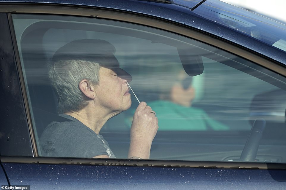 A woman winces as she does her own nasal swab at the NHS Test and Trace facility at Wavertree Sports Park on the first day of the swabbing pilot